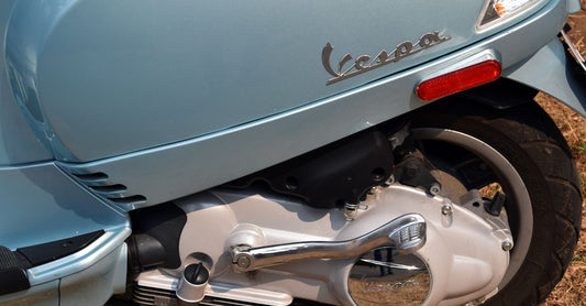Einseitige Vorderradaufhängung einer Vespa mit sichtbarer Schwinge und Schraubenfeder