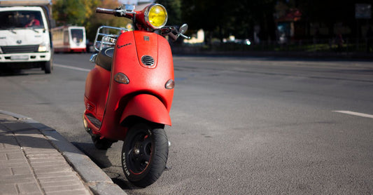 Rote Vespa GTS auf einer ruhigen Landstraße vor einer kurvigen Strecke